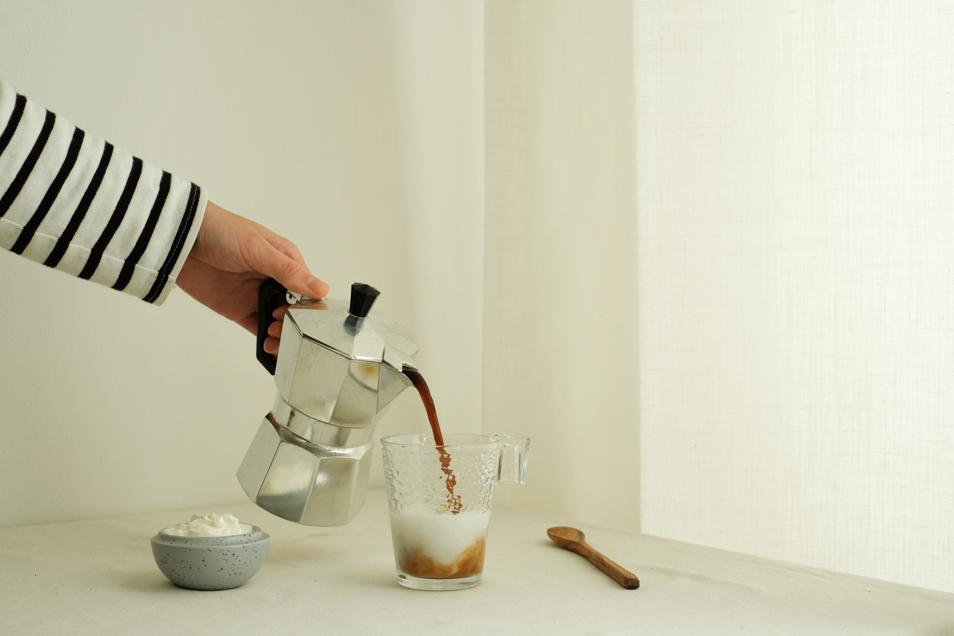 Hand Pouring Coffee into Mug with Milk